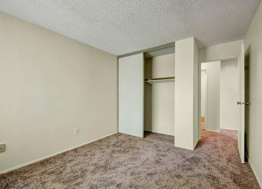 A comfortable bedroom at Lakewood Heights featuring soft carpet, neutral walls, a sliding-door closet for easy storage, and a simple layout that’s easy to personalize.