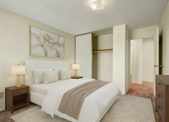 A calm, inviting bedroom here at Lakewood Heights with soft neutral walls, plush carpet, a comfortable bed with layered bedding, warm bedside lighting, and a sliding-door closet that adds convenient storage.