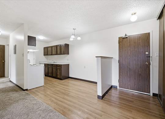 A kitchen area with a white fridge, wooden cabinets, and a brown door.