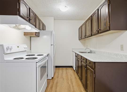 A kitchen with white appliances and brown cabinets.