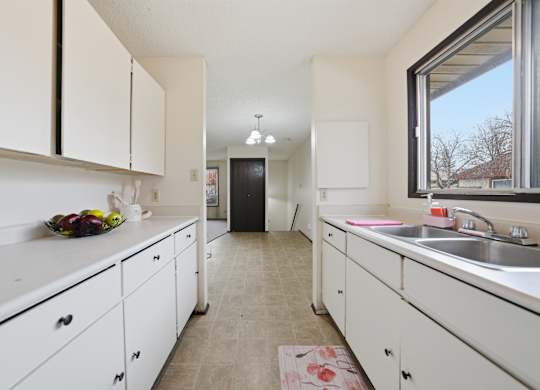 A kitchen with white cabinets and a sink.