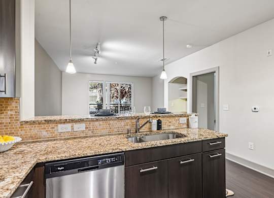 A kitchen with a granite countertop and stainless steel appliances.