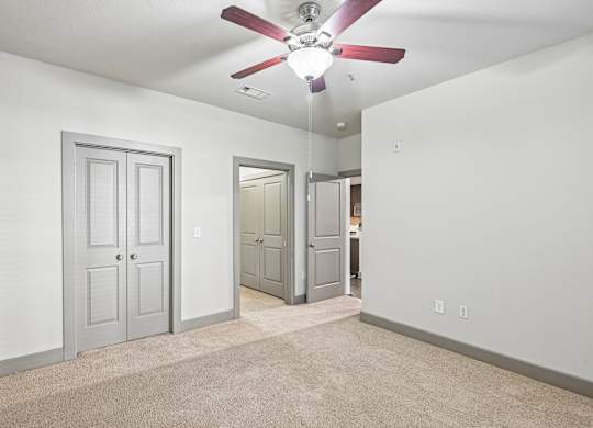 A room with a ceiling fan and carpeted floor.