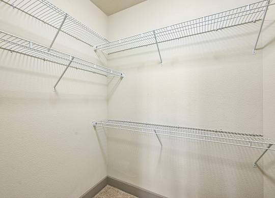 A white wall with three metal shelves.