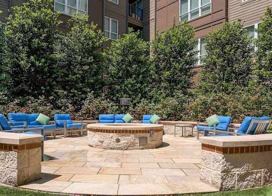 A patio with blue chairs and a fire pit.