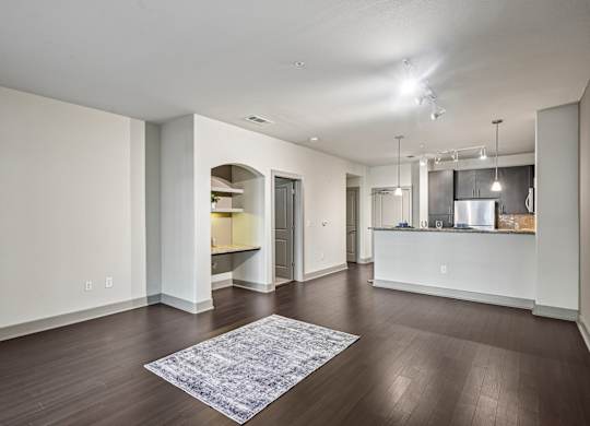 A spacious living room with a kitchen in the background.