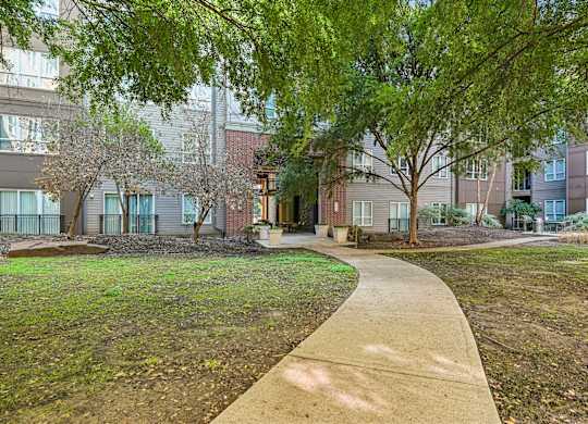 A walkway leads through a grassy area in front of apartment buildings.