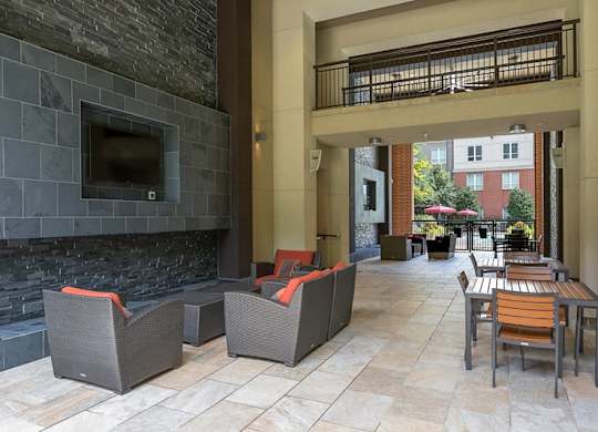 A patio with a stone fireplace and grey couches.