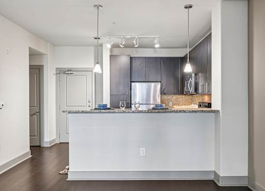 A modern kitchen with a white island and dark wood cabinets.
