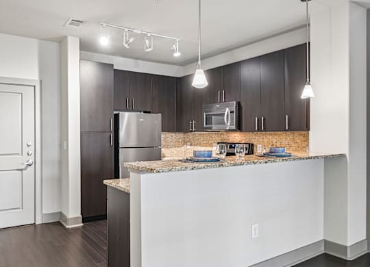 A kitchen with a refrigerator, microwave, and oven.
