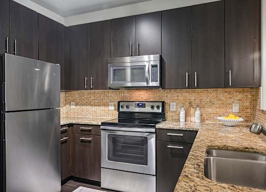 A kitchen with a stainless steel refrigerator, oven, and microwave.