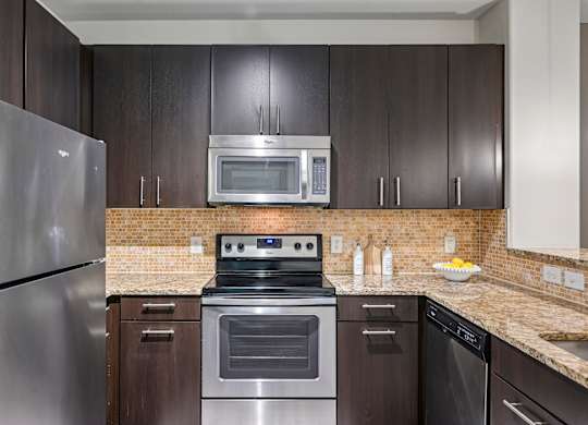 A modern kitchen with dark wood cabinets and stainless steel appliances.