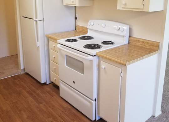 A white stove and refrigerator in a kitchen with wooden floors.