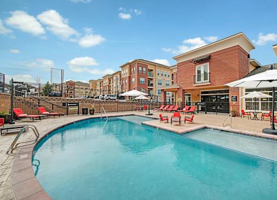 A swimming pool surrounded by red lounge chairs and umbrellas.