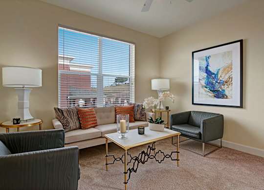 A living room with a sofa, armchair, and a painting on the wall.