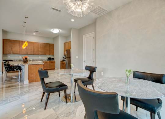 A modern dining room with a glass table and black chairs.