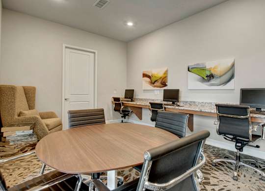 A conference room with a wooden table surrounded by chairs.