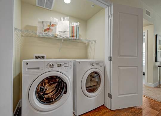 Two white front load washing machines in a laundry room.