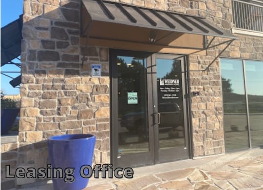 a leasing office with glass doors and a blue trash can