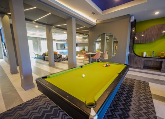 a pool table in a clubhouse with a yellow ball on it