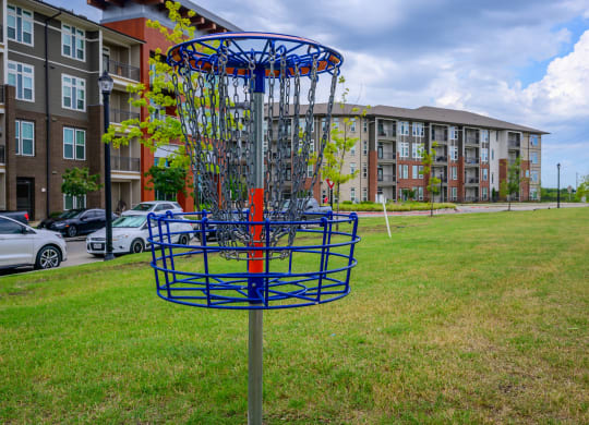 a frisbee hoop in the grass in front of an apartment building