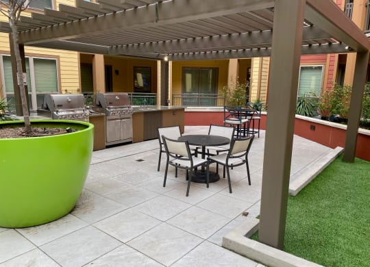 a patio with a table and chairs and a grill