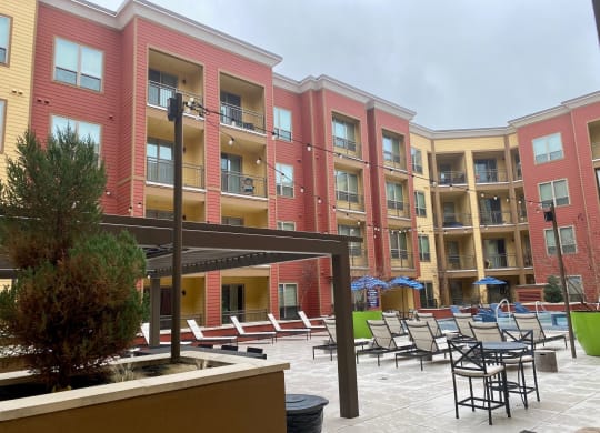 a courtyard with a pool and lounge chairs in front of an apartment building