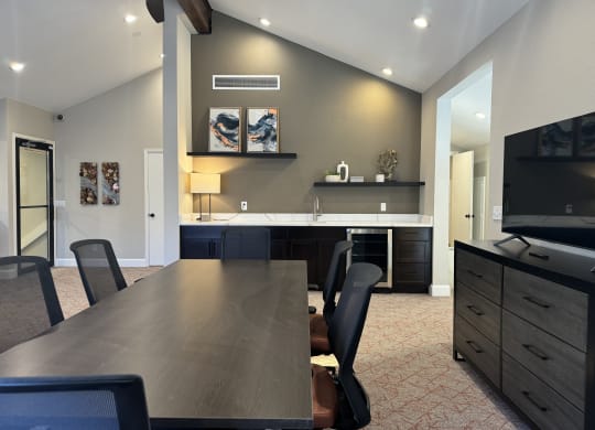 Modern kitchen here at Eagle Ridge Apartment Homes with a marble island, four brown chairs, and stylish black pendant lights. Light-gray walls feature abstract art, creating a chic ambiance.