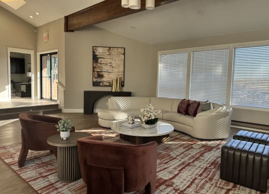 Spacious modern living room here at Eagle Ridge Apartment Homes with a white sectional sofa, red and white accents, abstract art, and large windows. Warm lighting and a cozy atmosphere.