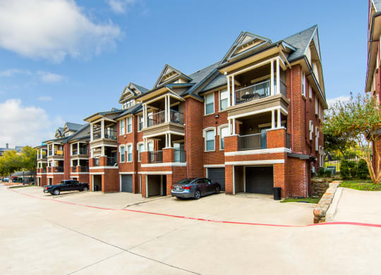 an empty parking lot in front of a brick apartment building