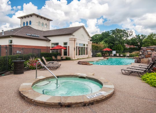 a pool with a hot tub in front of a house