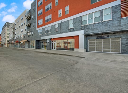 Street scene showing modern Latitude Apartment buildings with red and gray facades, large windows, and a parking garage.