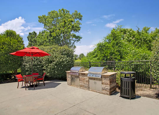 a patio with a barbecue grill and a table and chairs