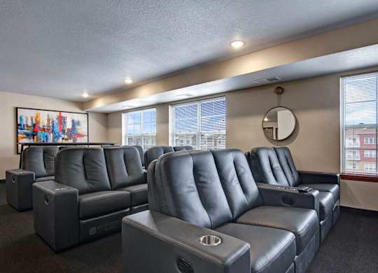 A private theater room here at Club at Heritage with plush reclining seating and built-in cup holders. Large windows and soft lighting create a comfortable space for movie nights and entertainment.