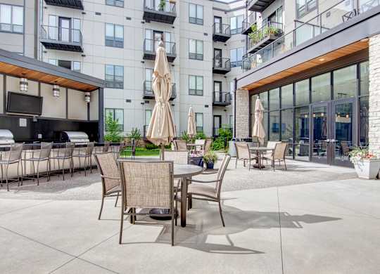 A patio area with chairs and tables is surrounded by apartment buildings.