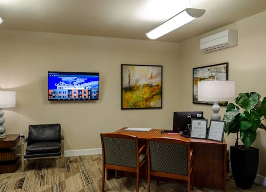 A room with a desk, chair, and a painting on the wall.