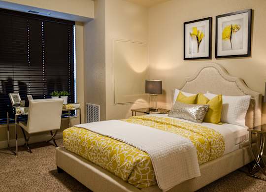 A bedroom with a large bed and a desk with a chair.