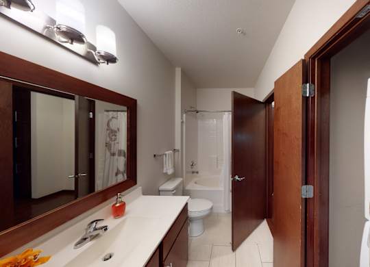 A bathroom with a toilet, sink, and mirror.