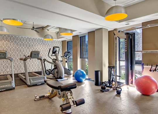 A gym with a variety of equipment including treadmills, exercise balls, and weights.