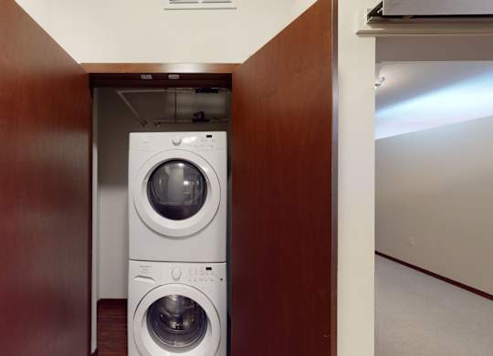 A washing machine is in a small space between a door and a wall.