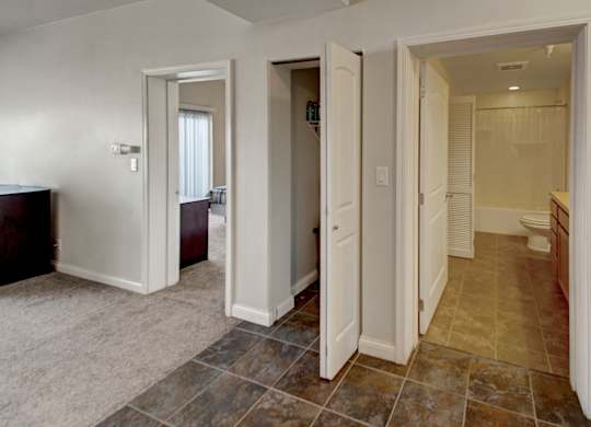 A hallway with a carpeted floor and tiled walls.