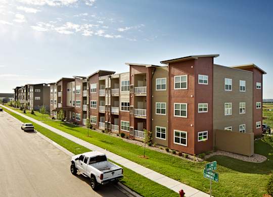 A row of apartment buildings with a white truck parked in front of the first one.