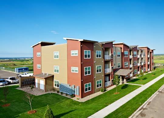 Apartment complex with a parking lot in front.