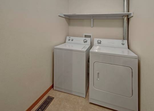 Two white front loading washing machines in a laundry room.