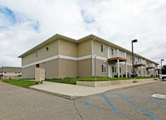Apartment building with a parking lot in front.