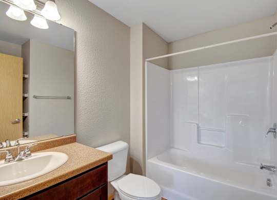 A bathroom with a white tub, sink, and toilet.