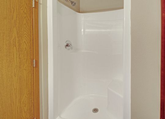 A white bathtub with a shower head and a drain in the middle.
