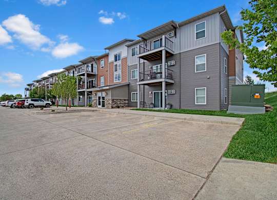 A large apartment complex with a parking lot in front.