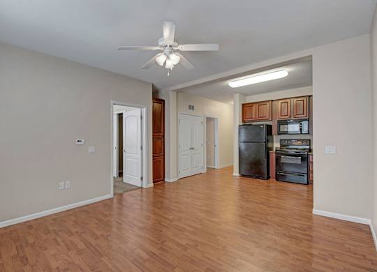 A room with a ceiling fan and wooden floors.