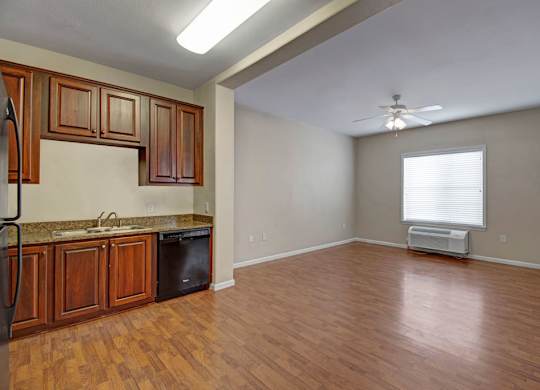 A kitchen with wooden cabinets and a black fridge.